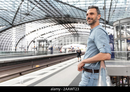 Lächelnder Mann am Bahnhof, der auf den Zug wartet, Berlin, Deutschland Stockfoto