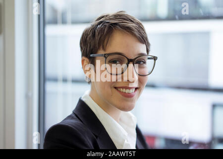 Portrait von lächelnden Jungen geschäftsfrau am Fenster Stockfoto