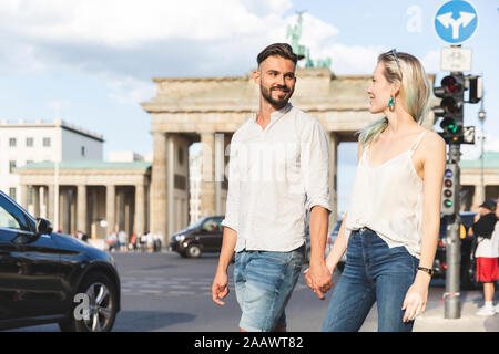 Glückliches junges Paar Hand in Hand vor dem Brandenburger Tor, Berlin, Deutschland Stockfoto