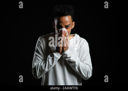Junge afrikanische amerikanische Mann niest in das Gewebe. Isolierte Mensch ist krank, hat eine Erkältung Stockfoto