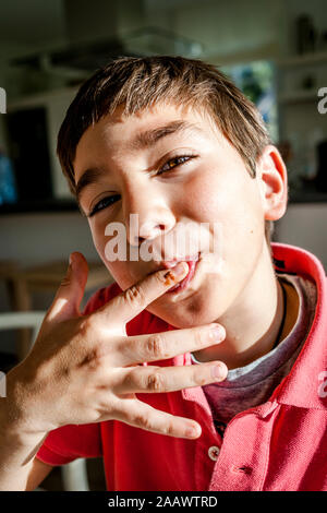 Portrait von Jungen zu Hause leckte sich die Finger Stockfoto