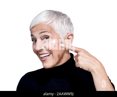 Portrait von reife Frau mit beauty Creme auf ihr Gesicht vor weißem Hintergrund Stockfoto