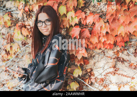 Portrait von Teenager mit Smartphone im Herbst Stockfoto