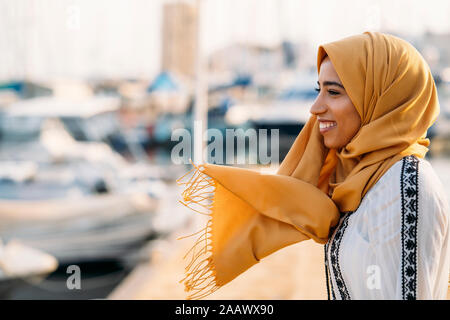 Junge muslimische Frau tragen gelbe Hijab zu Fuß am Hafen Stockfoto