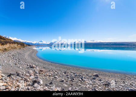 Neuseeland, Südinsel, klaren Himmel über felsigen Ufer des Sees Pukaki mit Bergen im Hintergrund Stockfoto