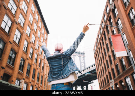 Frau mit Krebs bandana und erhobenen Armen an der Manhattan Bridge in New York, USA Stockfoto