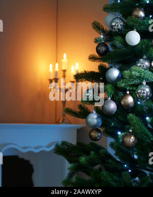 Kugeln am Weihnachtsbaum mit Kerzen brennen im Hintergrund zu Hause Stockfoto