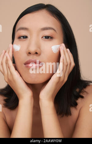 Porträt der jungen weiblichen chinesischen Frau Anwendung Creme Stockfoto