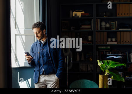 Mann, der in seinem Büro, Sie ihr Smartphone Stockfoto