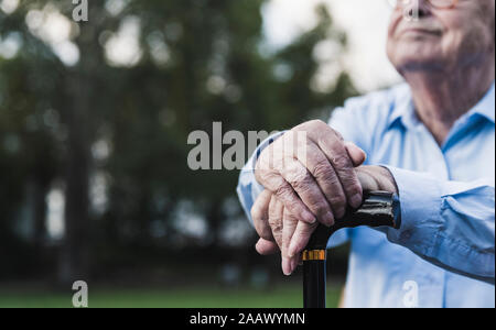 Hände von älteren Mann lehnte sich auf Gehstock, close-up Stockfoto