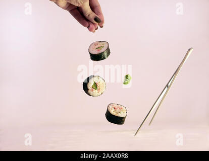 Sushi Stücke mit Stöcken flying auf weißem Hintergrund Stockfoto