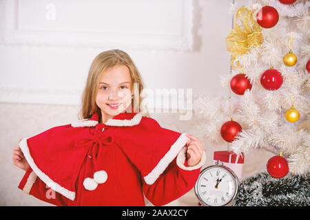 Kind Mädchen festliche Tracht in der Nähe der Weihnachtsbaum. Kindheit glück Konzept. Kind feiern Weihnachten zu Hause. Lieblings Tag des Jahres. Weihnachtsfeier. Unglaublich über Weihnachten aufgeregt. Stockfoto