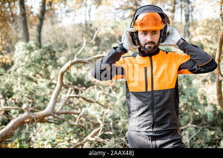 Taille - Porträt eines professionellen lumberman durch das Tragen von schützender Kleidung, die Vorbereitung für die Protokollierung der Arbeit in den Pinienwald Stockfoto