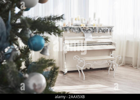Neues Jahr Dekoration. Weihnachtsbaum in der Nähe von white Klavier am Fenster Hintergrund Stockfoto