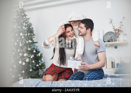 Glückliche Familie an Weihnachten Morgen Eröffnung gaben zusammen in der Nähe der Tanne. Das Konzept der Familie Glück und Wohlergehen Stockfoto