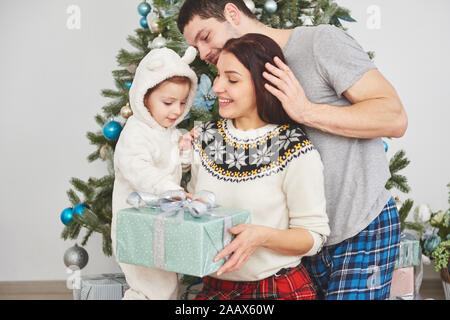 Glückliche Familie an Weihnachten Morgen Eröffnung gaben zusammen in der Nähe der Tanne. Das Konzept der Familie Glück und Wohlergehen Stockfoto