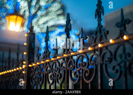 Iron Fleur de Lis, französischer Seerosenzaun und gelbe Laterne mit blauem Bokeh-Hintergrund. Stockfoto