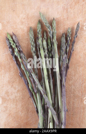 Mediterrane Küche - wilder Spargel auf dem hölzernen Tablett mit Pachino Tomaten Stockfoto