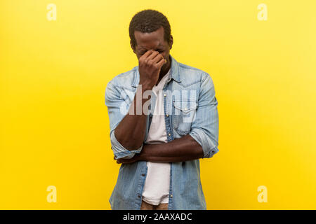 Portrait von depressiven hoffnungsloser Mann in Jeans casual Shirt mit aufgerollten Ärmeln verstecken Gesicht in der Hand und weinte, hart, hoffnungslos, und besorgt über Probl Stockfoto