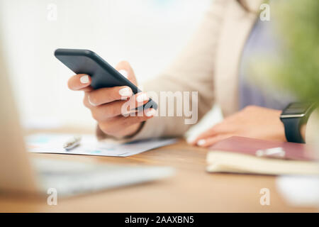 Nahaufnahme des unkenntlich Geschäftsfrau Text eingeben Nachricht während der Arbeit am Schreibtisch im Büro, auf weibliche Hand Smartphone kopieren Raum konzentrieren Stockfoto