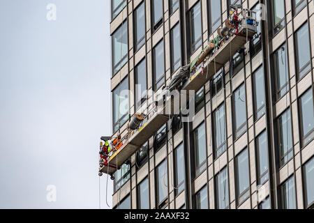 Hohes Arbeiter. Ein Wartung Arbeiter auf einer Hubarbeitsbühne hoch oben auf dem Gesicht von einem Bürogebäude in Philadelphia. Stockfoto