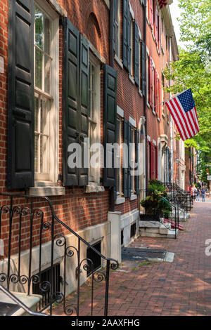 Die Sterne und Streifen hängt von einer von Bäumen gesäumten Reihe der historischen Häuser in der Pine Street, Society Hill. Stockfoto