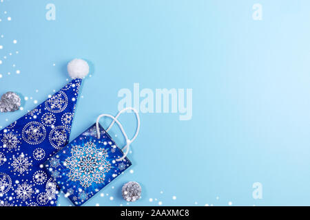 Weihnachten Vertriebskonzept mockup in Blau mit blauen Santa Hut, Geschenkbeutel, silberne Tannenzapfen und Schnee. Ansicht von oben, flach, kopieren. Stockfoto