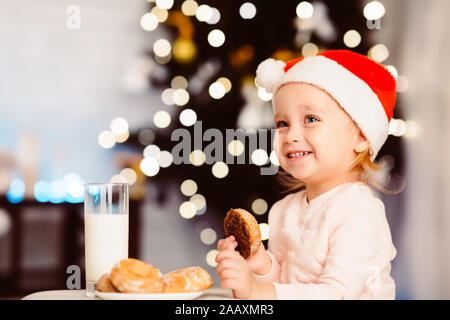 Adorable kleine Mädchen vorbereiten Milch und Kekse am Heiligabend Stockfoto