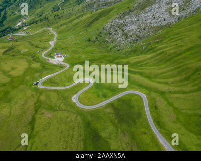 Luftaufnahme der asphaltierten Straße, Fahrbahn mit Wiese in Passo Giau, kurvenreiche Straße in Berg Tal im Sommer, Dolomiten, Italien. Stockfoto