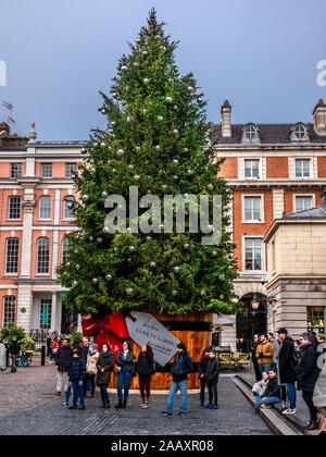 London, England, Großbritannien - 15 November, 2019: Weihnachten Szene outdoor mit Menschen rund um geschmückten Baum auf dem Marktplatz von Covent Garden im Winter Holi Stockfoto