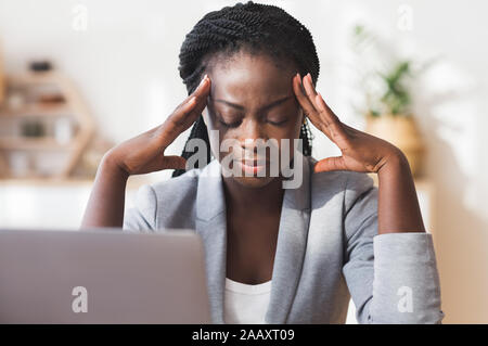 Afro Geschäftsfrau Massage Tempel, die versuchen, sich auf die Arbeit zu konzentrieren Stockfoto