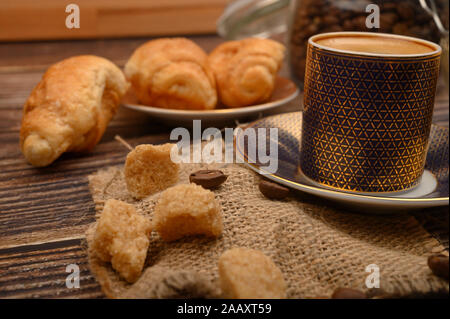 Eine Tasse Kaffee, brauner Zucker, Croissants auf einer hölzernen Hintergrund. Nahaufnahme Stockfoto