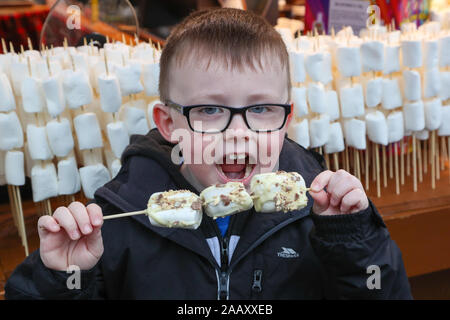 Glasgow, UK. 24. November 2019, im Rahmen der festlichen Glasgow's feiern, der jährliche Weihnachtsmarkt offiziell eröffnet in der Stadt George Square mit einem Jahrmarkt, Geschenkeladen und Chalets verkauf einer Auswahl an internationalen Speisen. George Square ist traditionell das Zentrum der Feierlichkeiten der Stadt und alle Ecken sind für Tausende von Touristen, die die Stadt und die Märkte besuchen wird vorbereitet. Bild von ROBBIE WHELAN, im Alter von 7 von Glasgow genießen Sie amerikanische gerösteten Marshmallows. Credit: Findlay/Alamy leben Nachrichten Stockfoto