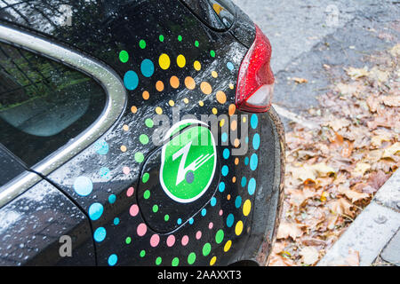 Nahaufnahme eines verregneten Zipcar Logo - ein amerikanisches Auto-sharing Unternehmen VW Polo auf einer Straße in London Stockfoto