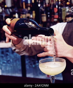 Barkeeper gießt Sekt im glassm getonten Bild Stockfoto