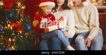 Kleines Mädchen in Santa Hut Eröffnung Weihnachtsgeschenk Stockfoto