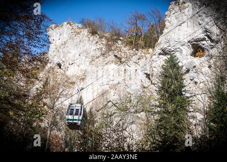 Seilbahn mit blauem Himmel und Felsen im Hintergrund. Kabel Kabine in Mähren. Macocha Kabel-Straßenbahn. Übersetzung von Text in Bild: Macocha Seilbahn. Stockfoto