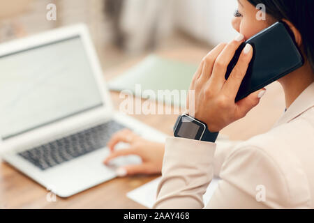 Hohen winkel Nahaufnahme der erfolgreiche Geschäftsfrau sprechen über das Telefon und mit Laptop, während am Schreibtisch im Büro arbeiten, kopieren Raum Stockfoto