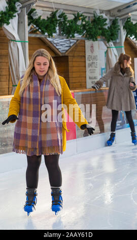 Schlittschuhläufer Spaß auf der Eislaufbahn auf Winchester Cathedral Eisbahn an der Winchester, Hampshire, UK im Dezember Stockfoto