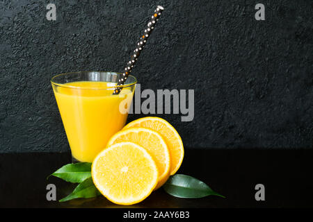 Glas orange und Orangenscheiben auf schwarzem Hintergrund. Stockfoto