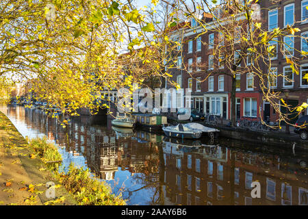 AMSTERDAM HOLLAND CANAL IM HERBST mit den goldenen Blätter an den Bäumen und Ästen HÄNGEND ÜBER DEM WASSER Stockfoto