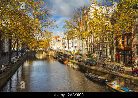 AMSTERDAM HOLLAND CANAL IM HERBST MIT DEN GOLDENEN BLÄTTER AN DEN BÄUMEN UND KLEINE BOOTE AUF DEM WASSER Stockfoto