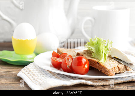 Frühstück im Landhausstil: Scheiben Getreidebrot mit Salat, Tomaten und Frischkäse. Stockfoto