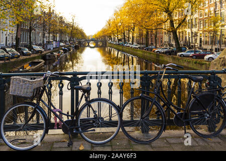 AMSTERDAM HOLLAND CANAL IM HERBST MIT DEN GOLDENEN BLÄTTER AN DEN BÄUMEN UND ZWEI FAHRRÄDER AUF DER BRÜCKE Stockfoto