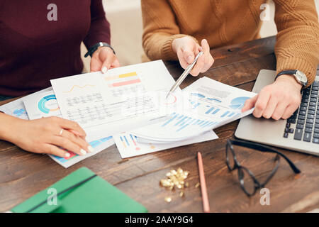 7/8-Porträt von zwei junge Geschäftsleute oder Studenten, der auf Daten Diagramme und Sitzen am Schreibtisch, beim Arbeiten oder Studieren Stockfoto