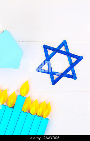 Menora, Dreidel, sevivon, der Stern von David mit ihren eigenen Händen auf einem weißen Holztisch. DIY für ein Kind. Feier Chanukah Stockfoto