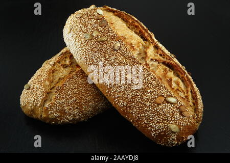 Zwei ganze hausgemachtes Brot Brot mit Buchweizen Buchweizen Mehl auf Schwarz strukturierten Hintergrund. Ansicht von oben oder flach-legen. Kopieren Sie Platz. Low Key Stockfoto