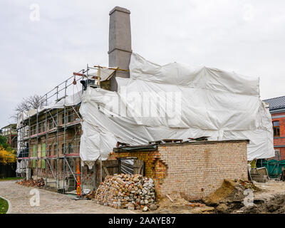 Wiederaufbau eines alten zweistöckigen Backsteinhaus, Fassade mit grünen Netz abgedeckt Stockfoto
