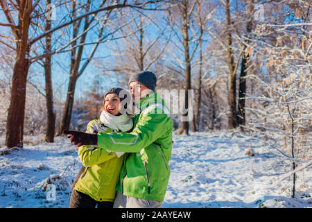 Aktivitäten im Winter. Paare, die in Liebe zu und umarmen im Winter Wald. Die jungen Menschen zeigen und suchen nach etwas Stockfoto