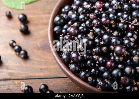 Reife schwarze Johannisbeeren in einem Ton Platte auf einem braunen Holz- Hintergrund. Platz für Text Stockfoto